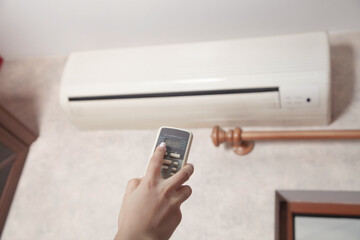 Fototapeta premium Female hand using remote controller for adjust Air conditioner.