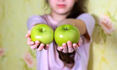 Fototapeta na wymiar The girl holds two green apples in her hands. Blurry.