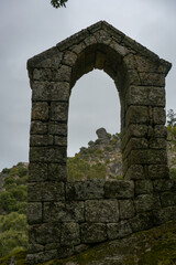 Ancient ruin stone structure building covered with moss near Sao Pedro chapel with trees and boulder landscape in Monsanto, Portugal