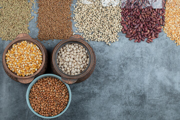 Assortment of raw beans, peas and corns on a marble background