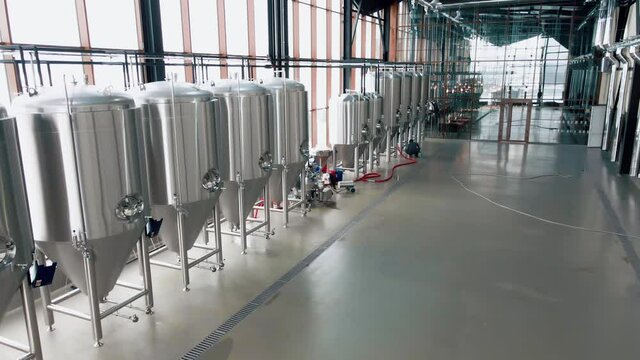 Shiny metal beer tanks at the modern brewery. Wide angle panoramic view, camera is moving