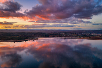 Drone aerial view of a lake reservoir of a dam with perfect reflection on the water of the sunset in Sabugal, Portugal