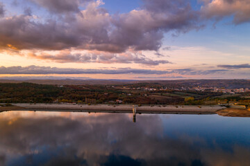 Drone aerial view of a lake reservoir of a dam with perfect reflection on the water of the sunset in Sabugal, Portugal