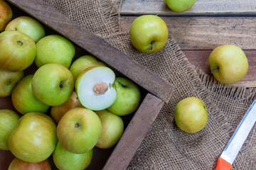 Fresh and ripe indian Jujube fruits in a basket with knife on wooden background.
