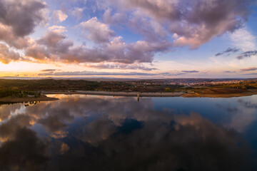 Obraz premium Drone aerial view of a lake reservoir of a dam with perfect reflection on the water of the sunset in Sabugal, Portugal