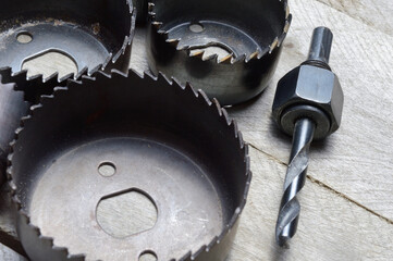 a set of old crowns for drilling a tree lies on a plank, wooden background. close-up.