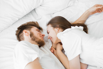 guy and girl lie on a white bed. Flat lay top-down