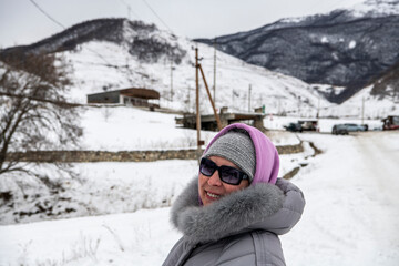 Fototapeta na wymiar woman in a gray jacket travels in winter in the Caucasus mountains and admires the sights