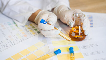 Woman making urine test with ph material in laboratory. Female hands in gloves and a flask of urine...