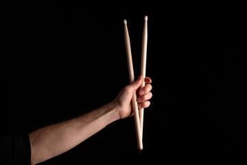Two drumsticks in male hand on dark background