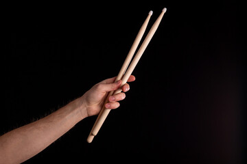 Two drumsticks in male hand on dark background