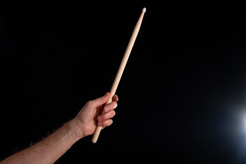 A drumstick in male hand on dark background