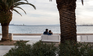 A couple in love on a bench by the sea,view from behind.