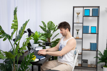 A young employee sits at a desk and types on a laptop keyboard. Remote work at home. A domain...