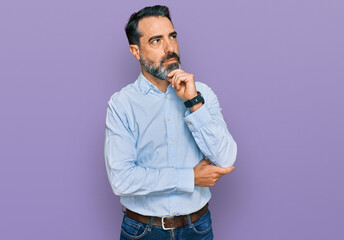 Middle aged man with beard wearing business shirt with hand on chin thinking about question,...