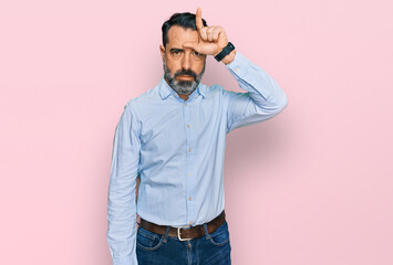 Middle aged man with beard wearing business shirt making fun of people with fingers on forehead...