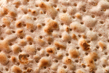 Hand-made matzah on Pesach holiday. Top view of flatbread matzo, macro, background.