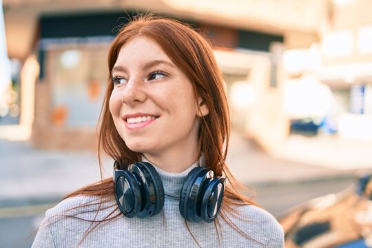 Young irish teenager girl smiling happy using headphones at the city.