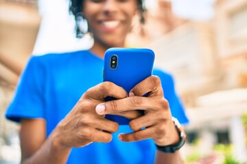 Young african american man smiling happy using smartphone at street of city.
