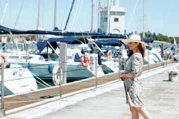 happy trendy solo traveller woman in floral dress on pier