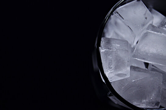 Half a glass full of ice cubes view on a black background view from above close up with copy space. High quality photo