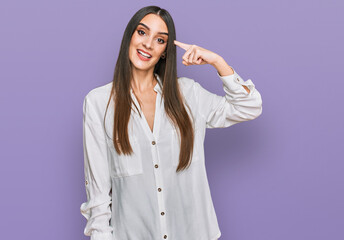 Young beautiful woman wearing casual white shirt smiling pointing to head with one finger, great idea or thought, good memory