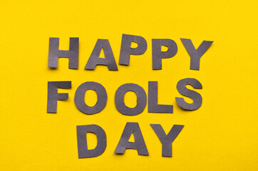 Obraz premium Image caption Happy Fool's Day of grey paper letters on a yellow background close-up. High quality photo