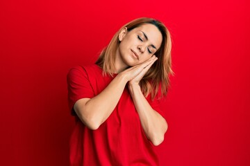 Hispanic young woman wearing casual red t shirt sleeping tired dreaming and posing with hands together while smiling with closed eyes.