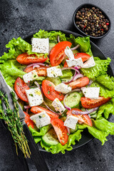 Fresh Greek salad with vegetables and feta cheese in a plate. Black background. Top view