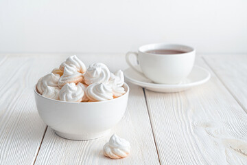 Obraz na płótnie Canvas Delicate meringues on a white background with a cup of tea. Side view.