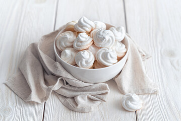 Fototapeta na wymiar Delicate meringues on a white background with a cup of tea. Side view.Airy meringue on a light background with a napkin.