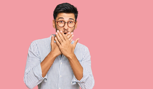Young handsome man wearing casual clothes and glasses shocked covering mouth with hands for mistake. secret concept.