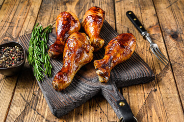 Barbecue roasted chicken drumsticks on a wooden cutting board. wooden background. top view