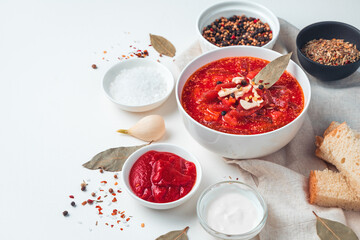 Delicious borscht with garlic and bay leaf on a white background.Vegetable soup with tomato and beetroot, bread, garlic and sour cream on a white background.