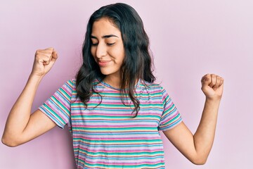 Obraz premium Hispanic teenager girl with dental braces wearing casual clothes showing arms muscles smiling proud. fitness concept.