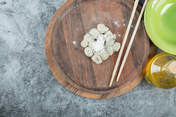 Raw dumplings with flour on a wooden board