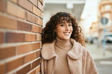 Young hispanic woman smiling happy standing at the city