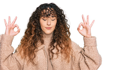 Young hispanic girl wearing winter clothes relax and smiling with eyes closed doing meditation gesture with fingers. yoga concept.
