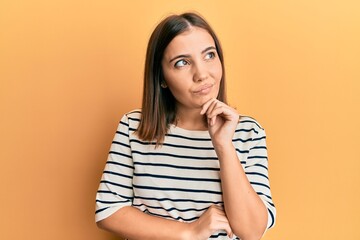 Young beautiful woman wearing casual striped t shirt thinking concentrated about doubt with finger on chin and looking up wondering