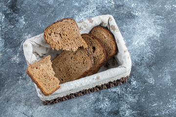Slices of brown bread on a basket on a gray background