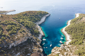 Aerial drone shot of yachts in Adriatic sea cove Stiniva on Vis Island in Croatia summer morning