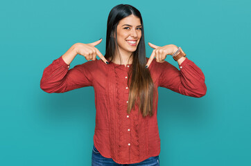 Young hispanic woman wearing casual clothes looking confident with smile on face, pointing oneself...