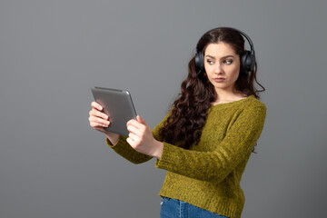 Naklejka premium young woman with headset and tablet in hand playing games and talking to friends online