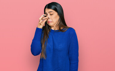 Young hispanic woman wearing casual clothes smelling something stinky and disgusting, intolerable smell, holding breath with fingers on nose. bad smell - obrazy, fototapety, plakaty