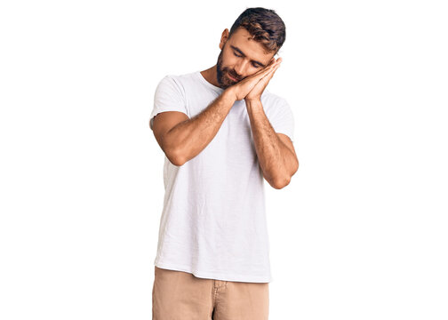 Young Hispanic Man Wearing Casual White Tshirt Sleeping Tired Dreaming And Posing With Hands Together While Smiling With Closed Eyes.