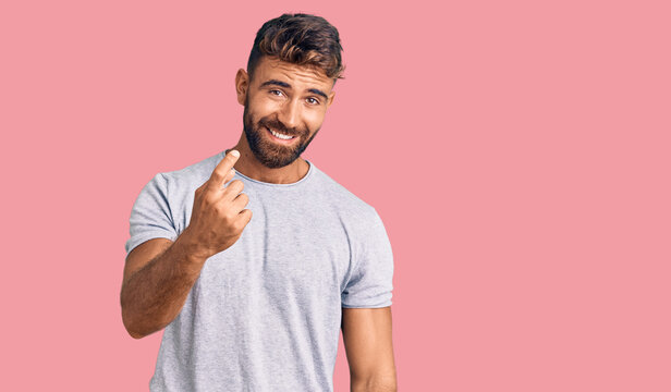 Young hispanic man wearing casual clothes beckoning come here gesture with hand inviting welcoming happy and smiling