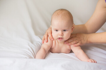 Happy infant girl doing baby massage by his mother at home. Newborn child about 5 months old