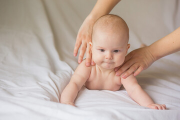 Happy infant girl doing baby massage by his mother at home. Newborn child about 5 months old