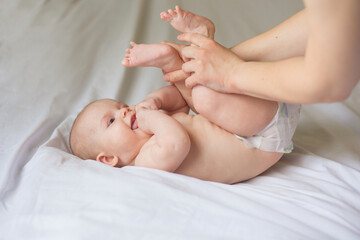 Happy infant girl doing baby massage by his mother at home. Newborn child about 5 months old