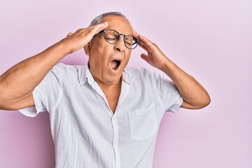 Handsome mature senior man wearing casual shirt and glasses with hand on head, headache because stress. suffering migraine.